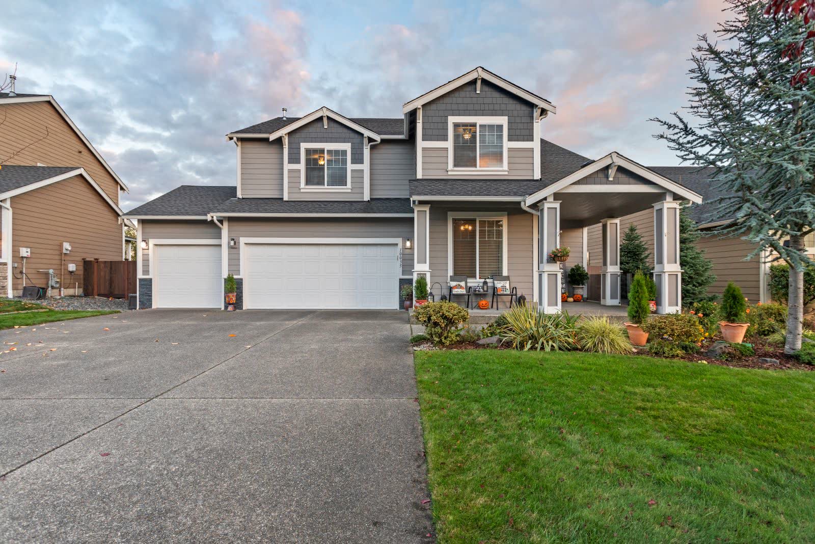 A finished pale concrete driveway running up to a two-car garage beside a trimmed lawn